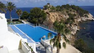 a swimming pool next to the ocean with palm trees at Apartamento Panorama 180º in Altea
