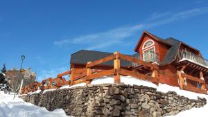 una cabaña de madera en la nieve con una pared de piedra en Great Chalet Farellones, en Farellones