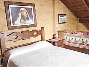 ein Schlafzimmer mit einem Bett und ein Gemälde einer Nonne in der Unterkunft Recanto Marazul in Ubatuba