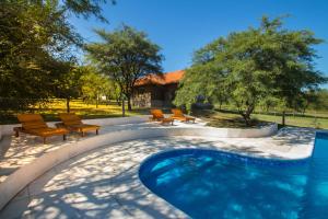 a swimming pool with chairs and a house at El Refugio Casas de Campo in Villa General Belgrano
