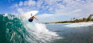 una persona montando una ola en una tabla de surf en el océano en Weligama Oriental Villa, en Weligama