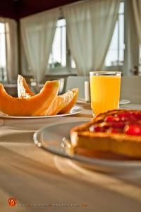 two plates of oranges and a glass of orange juice on a table at Hotel Esmeralda in Piriápolis