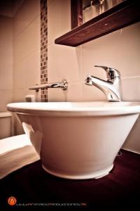 lavabo blanco con grifo en el baño en Hotel Esmeralda, en Piriápolis