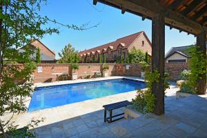 a swimming pool in a yard with a brick building at Compass Cottage - Monaco Resort in Nelson