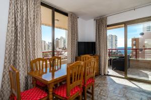 ein Esszimmer mit einem Tisch und Stühlen sowie einem Balkon in der Unterkunft CarlosV in Benidorm