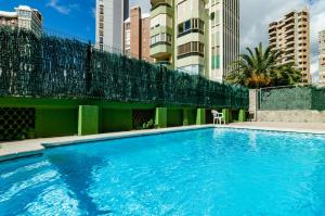 ein großer blauer Pool neben einem hohen Gebäude in der Unterkunft CarlosV in Benidorm
