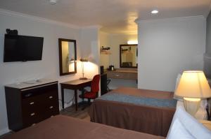 a hotel room with two beds and a desk and a television at Welcome Inn Corona in Corona