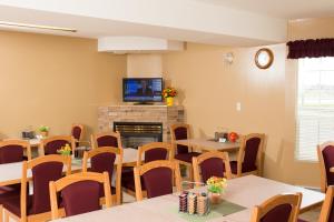 uma sala de jantar com mesas e cadeiras e uma lareira em Western Budget Motel East Red Deer em Red Deer