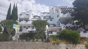 un grand bâtiment blanc avec des arbres devant lui dans l'établissement Pueblo Evita Hill, à Benalmádena