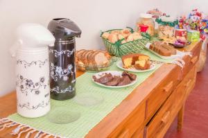 ein Holztisch mit Brot und Gebäck darauf in der Unterkunft Pouso copo de leite in Tiradentes