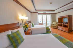 a hotel room with two beds and a television at Hotel Casa Veranda Guatemala in Guatemala
