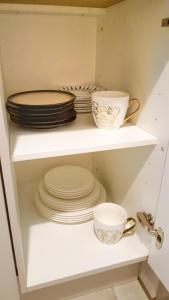 a white shelf with plates and cups on it at Bremen Apartments Nath Schnoor in Bremen
