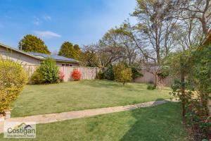 einen Hinterhof mit einem Zaun und einem Garten mit Gras in der Unterkunft The Summit House in Katoomba