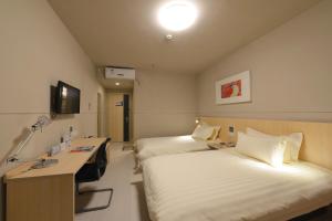 a hospital room with two beds and a desk at Jinjiang Inn Suzhou Railway Station North Square in Suzhou