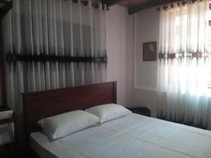 a bedroom with a bed with white sheets and curtains at Walawwa Guest House in Matale