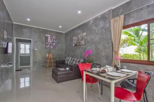 a living room with a table and red chairs at Maikhao Home Garden Bungalow in Mai Khao Beach