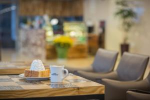 a cup of coffee and a piece of cake on a table at Gloucester Hotel Jeju in Jeju