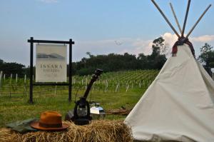 Issara Boutique Winery Hotel في مواكليك: قبعة وخيمة في حقل مع علامة