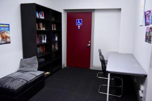 a room with a red door and a desk with a laptop at The Emperors Crown Hostel in Perth