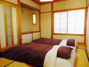 um quarto com uma cama grande num quarto com janelas em Utatei Villa em Takayama