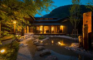 ein Haus mit einem Teich im Garten bei Nacht in der Unterkunft Kurotake in Achi
