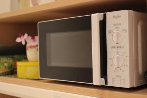 a microwave oven sitting on a shelf at Guesthouse COCO Hiroshima (Female Only) in Hiroshima