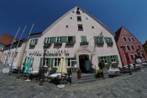 un bâtiment avec des tables et des chaises devant lui dans l'établissement Hotel-Landgasthof Schuster, à Greding