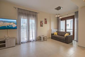 uma sala de estar com um sofá e uma televisão de ecrã plano em All Seasons Villas em Gállos