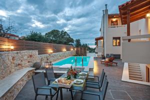 un patio con mesa y sillas junto a una piscina en All Seasons Villas en Gállos
