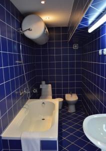 a blue tiled bathroom with a tub and a toilet at Hotel Shterev Sopot in Sopot