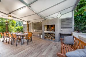 un patio con mesa, sillas y chimenea en Villa Lovran, heated pool and Spa en Lovran
