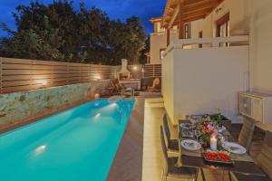 a pool with a table and chairs next to a house at All Seasons Villas in Gállos