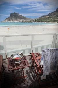 a balcony with two chairs and a table and a beach at 1 on Beach in Hout Bay
