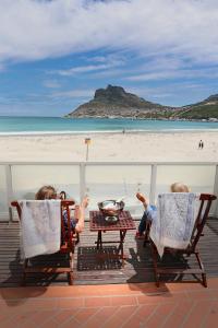 two people sitting in chairs on the beach with drinks at 1 on Beach in Hout Bay