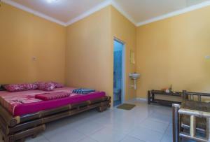 a bedroom with a bed in a room with yellow walls at Kumojoyo Homestay in Borobudur +57 photos