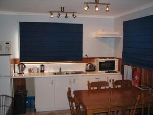 cocina con mesa y cocina con persianas azules en Derwent Bridge Chalets & Studios, en Derwent Bridge