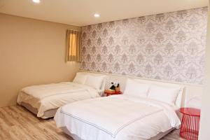 duas camas sentadas uma ao lado da outra num quarto em 星月文旅溫泉民宿 em Houli