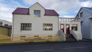 a white house with red doors and a yellow fence at Steinhúsið in Hólmavík