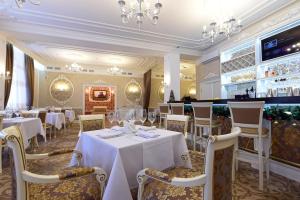 アンガルスクにあるPremium Hotel Pushkinの白いテーブルと椅子、シャンデリアのあるレストラン