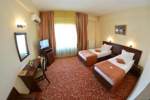 una camera d'albergo con due letti e uno specchio di Hotel Central a Ploieşti