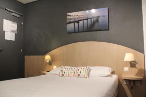 a bedroom with a bed and a painting on the wall at Hôtel Vol de Nuit Purpan in Toulouse