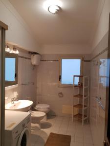 y baño con aseo, lavabo y lavadora. en XXI Agosto Home, en Reggio Calabria