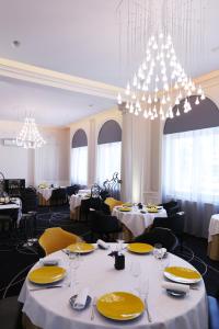 a restaurant with white tables and yellow chairs and chandeliers at Château Blanchard in Chazelles-sur-Lyon