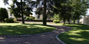 un chemin dans un parc planté d'arbres et d'herbe dans l'établissement Château Blanchard, à Chazelles-sur-Lyon