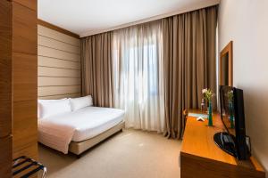um quarto de hotel com uma cama e uma televisão em Occidental Aurelia em Roma
