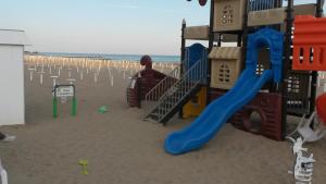 um parque infantil na praia com escorrega em Hotel Taormina em Lido di Jesolo