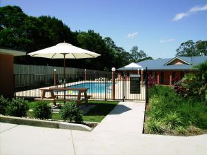 a fence with a table and an umbrella next to a pool at Seminara Apartments Coochiemudlo Island in Coochiemudlo