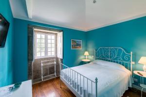 a blue bedroom with a bed and a window at Quinta de Luou in Santa Cruz do Lima