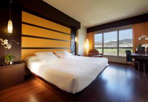 een slaapkamer met een groot wit bed en een bureau bij Hotel Abades Nevada Palace in Granada