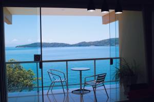 a balcony with a table and chairs and a view of the ocean at Ocean Green Flats in Angra dos Reis
